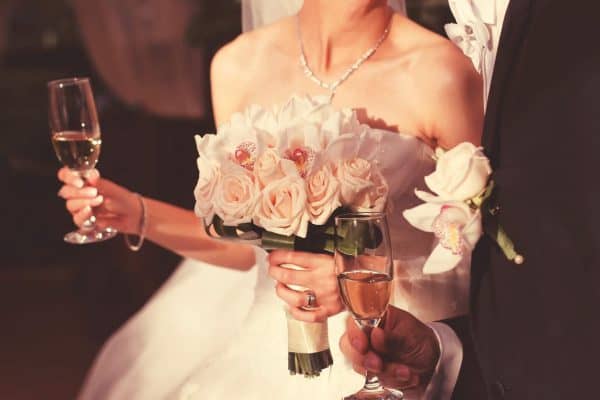 A bride and groom holding wine on their wedding day